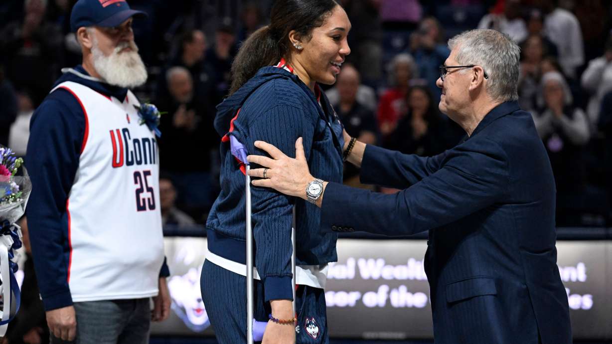 UConn head coach Geno Auriemma, right, reaches for UConn forward Ice Brady, center, as she is honored in a Senior Day ceremony after an NCAA college basketball game against Providence, Sunday, Feb. 22, 2026, in Storrs, Conn.