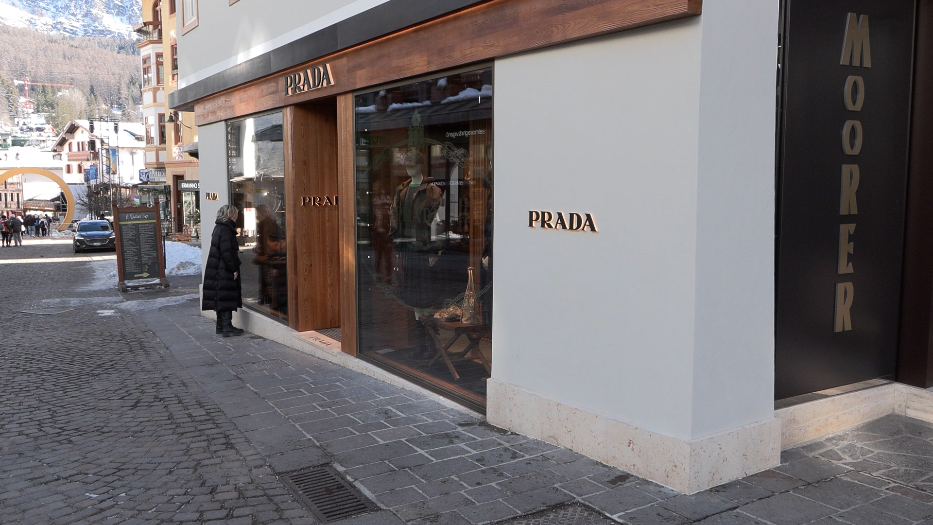 A woman gazes inside a Prada outlet storefront — an example of the luxury shopping found in Cortina.