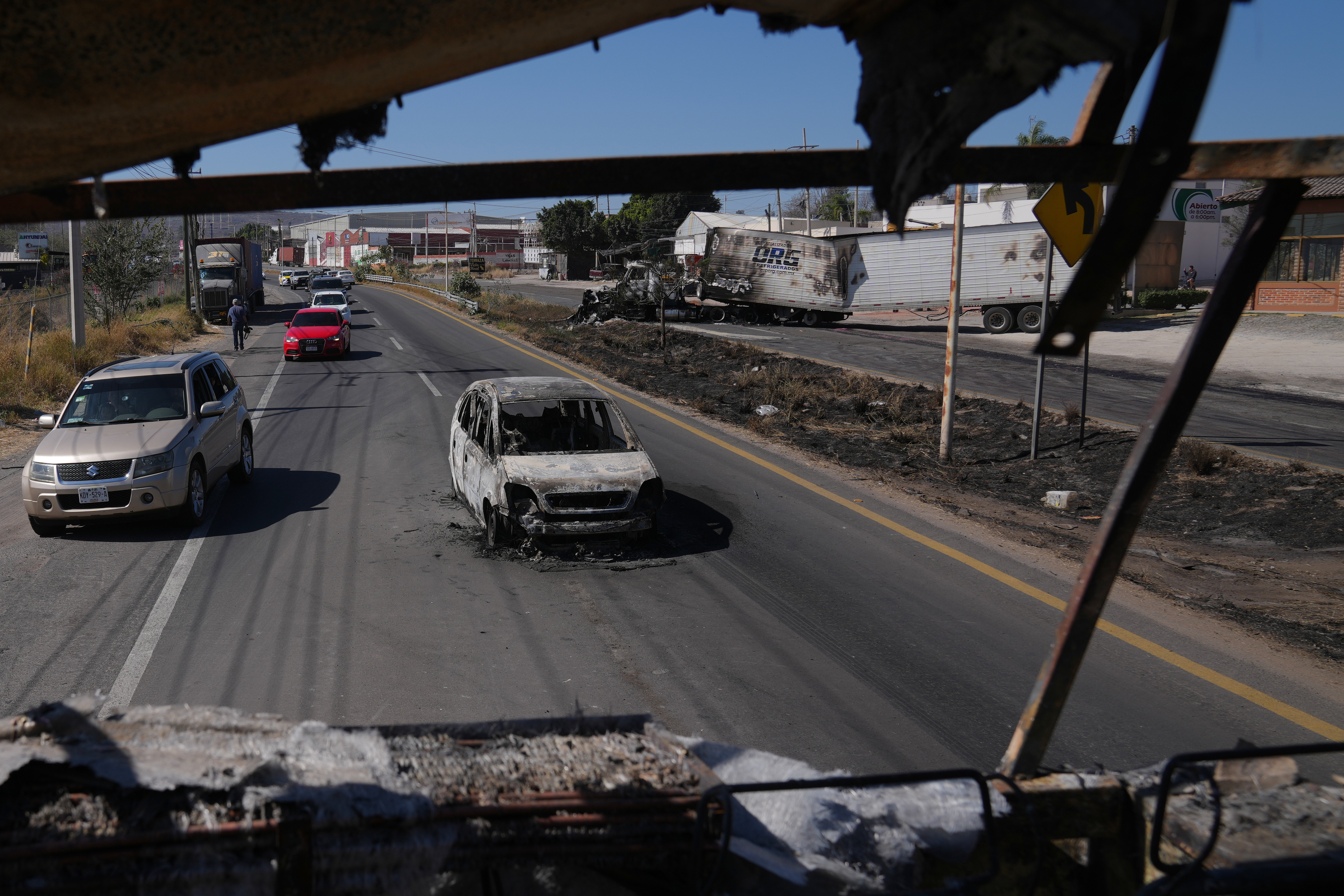 Vehicles pass a burned car a day after the Mexican army killed the leader of the Jalisco New Generation Cartel, Nemesio Oseguera Cervantes, known as "El Mencho," in Guadalajara, Mexico, Monday, Feb. 23, 2026. 