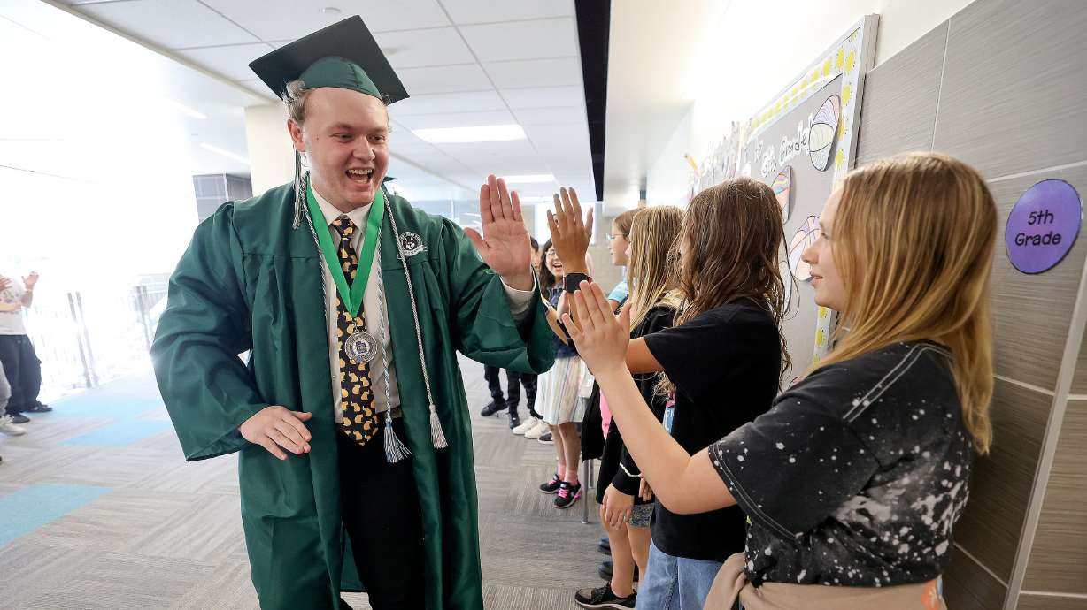 Soon-to-be Hillcrest High School graduate Seth Price high-fives students at Midvalley Elementary School in Midvale on May 23. A recent national analysis showed Utah earned strong marks in preparing high schoolers for post-graduation life.