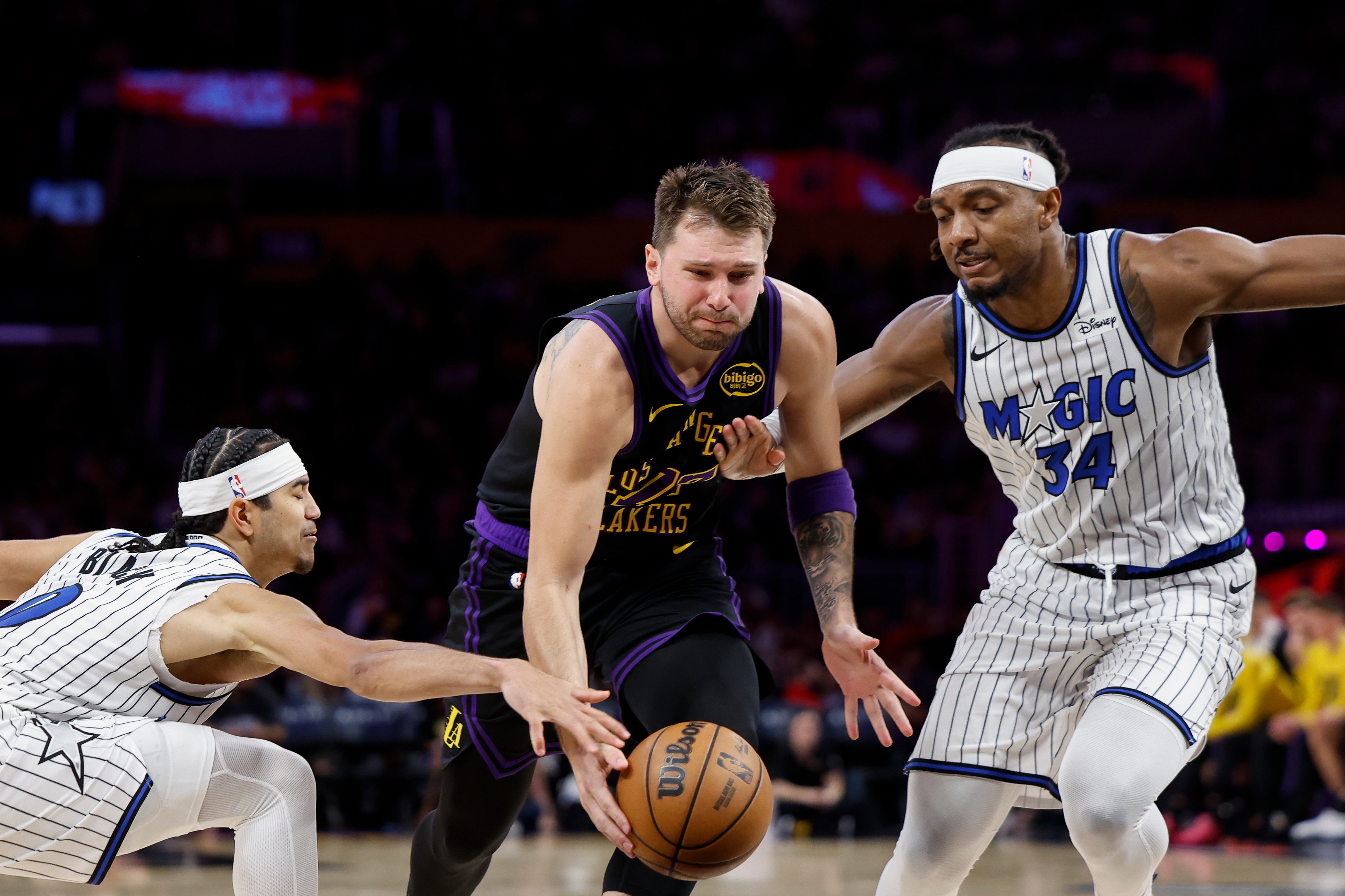 Los Angeles Lakers guard Luka Doncic (77) runs with the ball while being guarded by Orlando Magic guard Anthony Black (0) and Orlando Magic center Wendell Carter Jr. (34) during the second half of an NBA basketball game Tuesday, Feb. 24, 2026, in Los Angeles. 