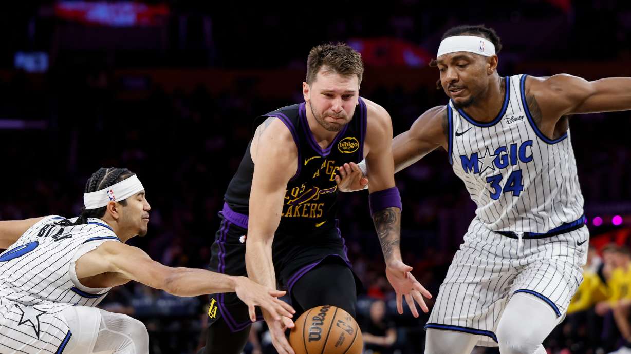 Los Angeles Lakers guard Luka Doncic (77) runs with the ball while being guarded by Orlando Magic guard Anthony Black (0) and Orlando Magic center Wendell Carter Jr. (34) during the second half of an NBA basketball game Tuesday, Feb. 24, 2026, in Los Angeles.