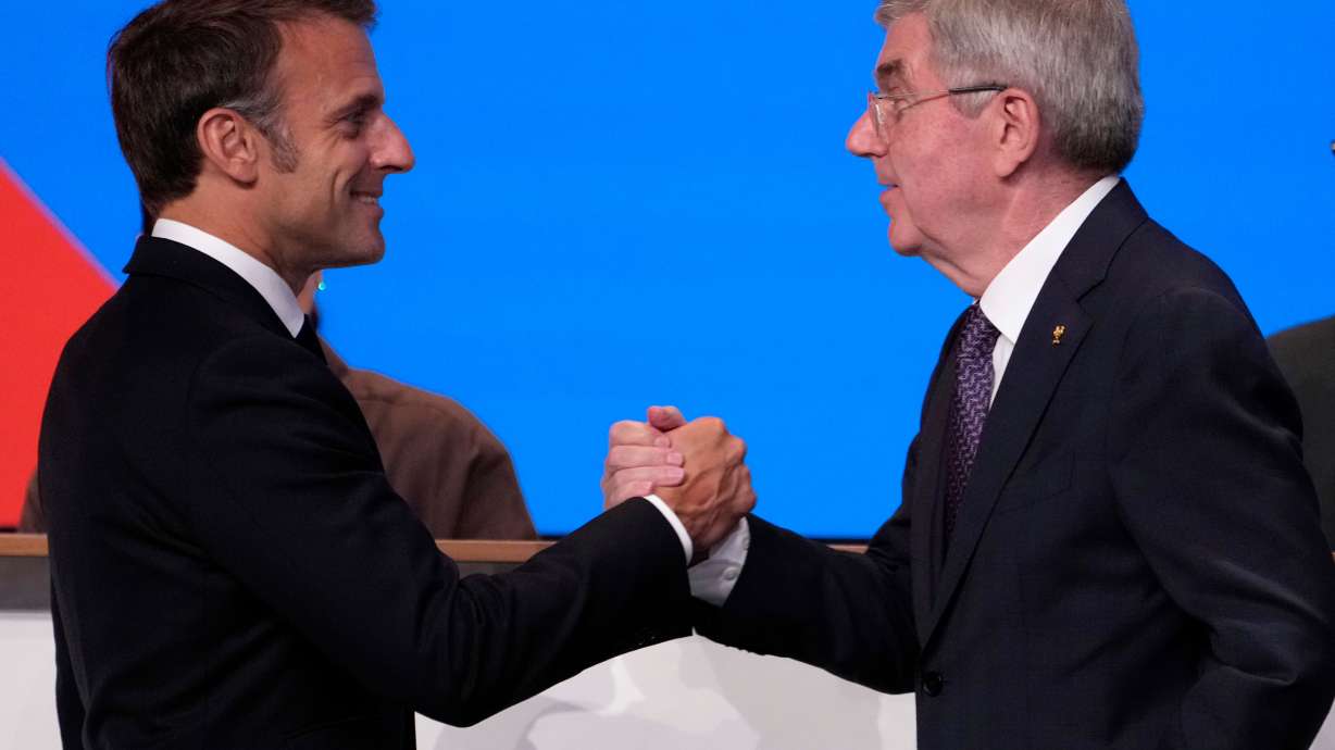 FILE - IOC president Thomas Bach, right, shakes hands to French President Emmanuel Macron after Bach announced that the French Alps was named as the 2030 Winter Games host at the 2024 Summer Olympics, Wednesday, July 24, 2024, in Paris, France.