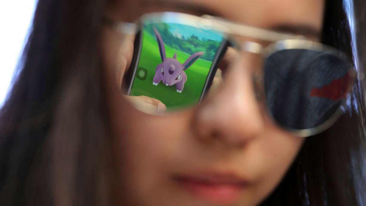 A mobile screen is reflected on a fan's sunglasses as she plays "Pokémon Go" in Hong Kong, on July 25, 2016. Fans are still trying to catch 'em all, 30 years after Pokémon's release.