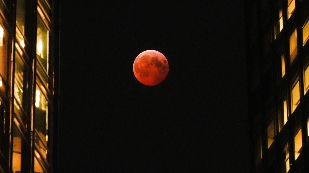 A total lunar eclipse, known as the blood moon, is visible between skyscrapers, March 14, 2025, in downtown Chicago. A total lunar eclipse will be seen Tuesday across several continents.