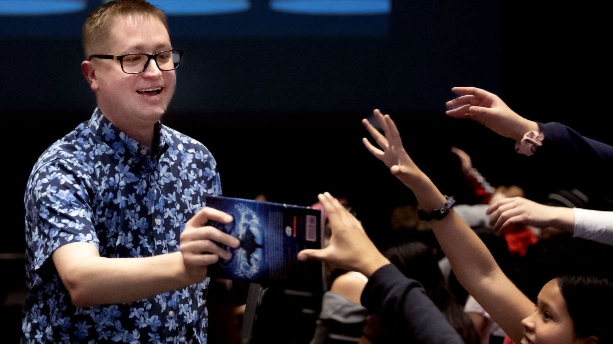 Author John Schu hands out free books to students during Operation Literacy at Bryant Middle School in Salt Lake City on Friday. Hundreds of Salt Lake City School District students received free books as part of Operation Literacy's book drop event.