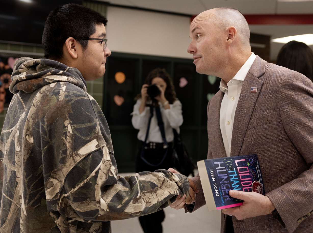 Marcos Ledesma, an eighth grader, receives a book from Gov. Spencer Cox during Operation Literacy at Bryant Middle School in Salt Lake City on Friday. Hundreds of students received free books as part of the book drop event.