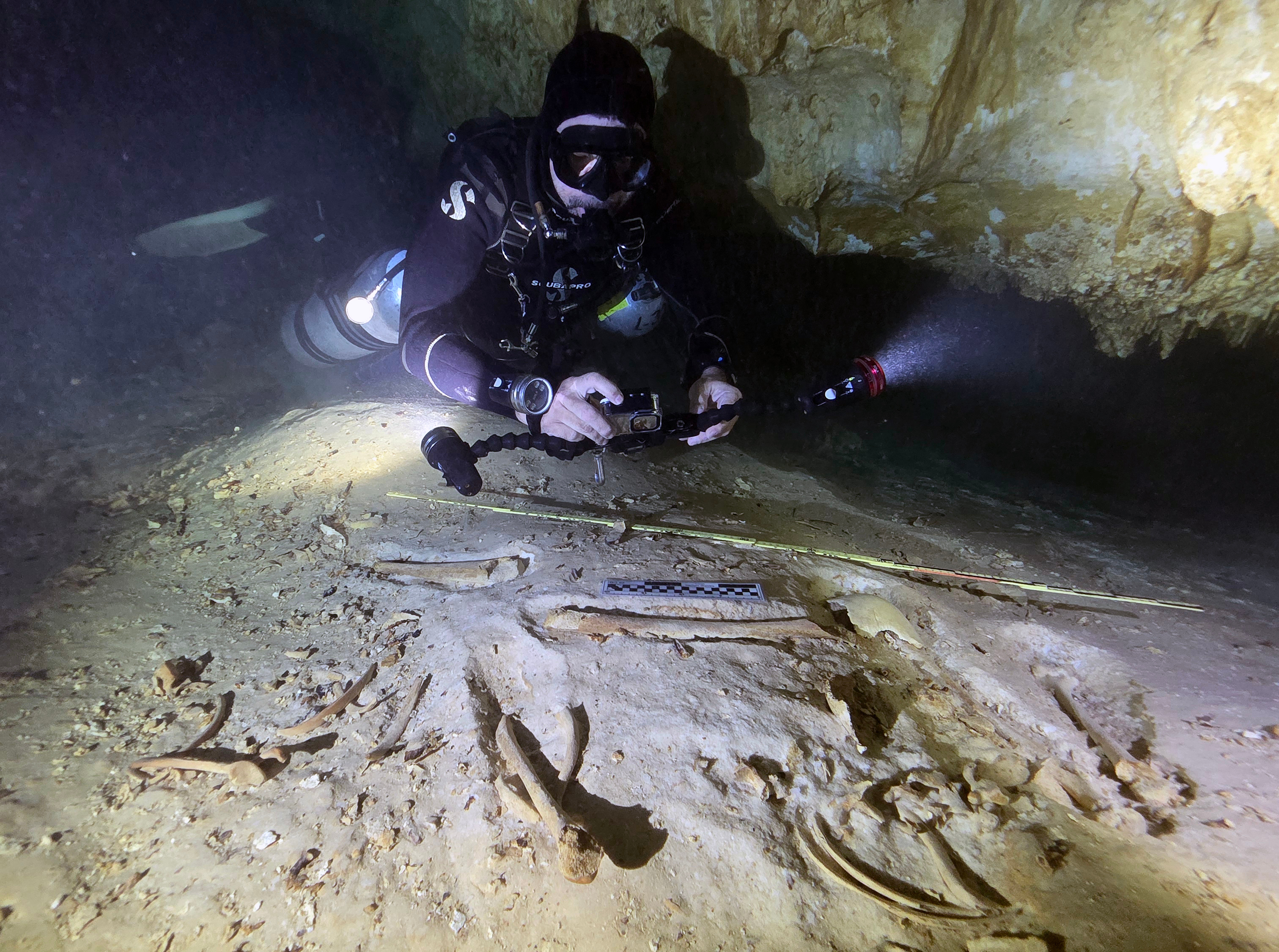 In this handout photo provided by the National Institute of Anthropology and History, underwater archaeologist Octavio del Río takes photos of the remains of a prehistoric human skeleton discovered inside the flooded cave system in Actun, near Tulum, Mexico, Nov. 18, 2025. 