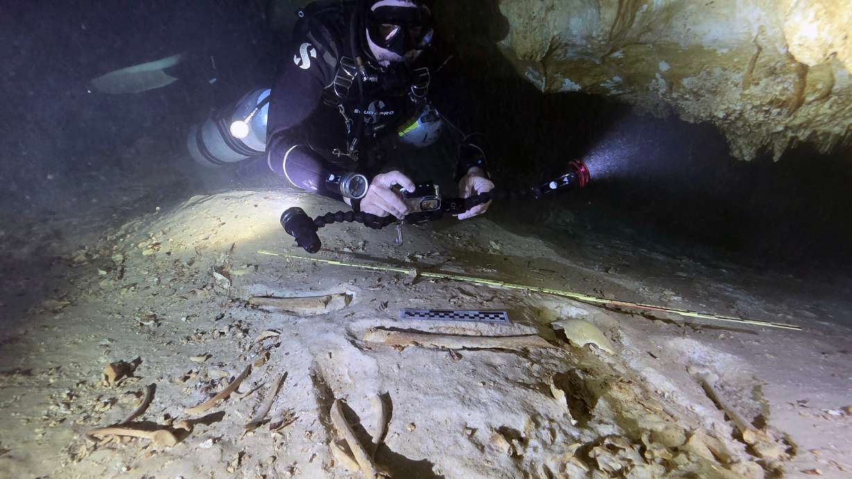 In this handout photo provided by the National Institute of Anthropology and History, underwater archaeologist Octavio del Río takes photos of the remains of a prehistoric human skeleton discovered inside the flooded cave system in Actun, near Tulum, Mexico, Nov. 18, 2025.
