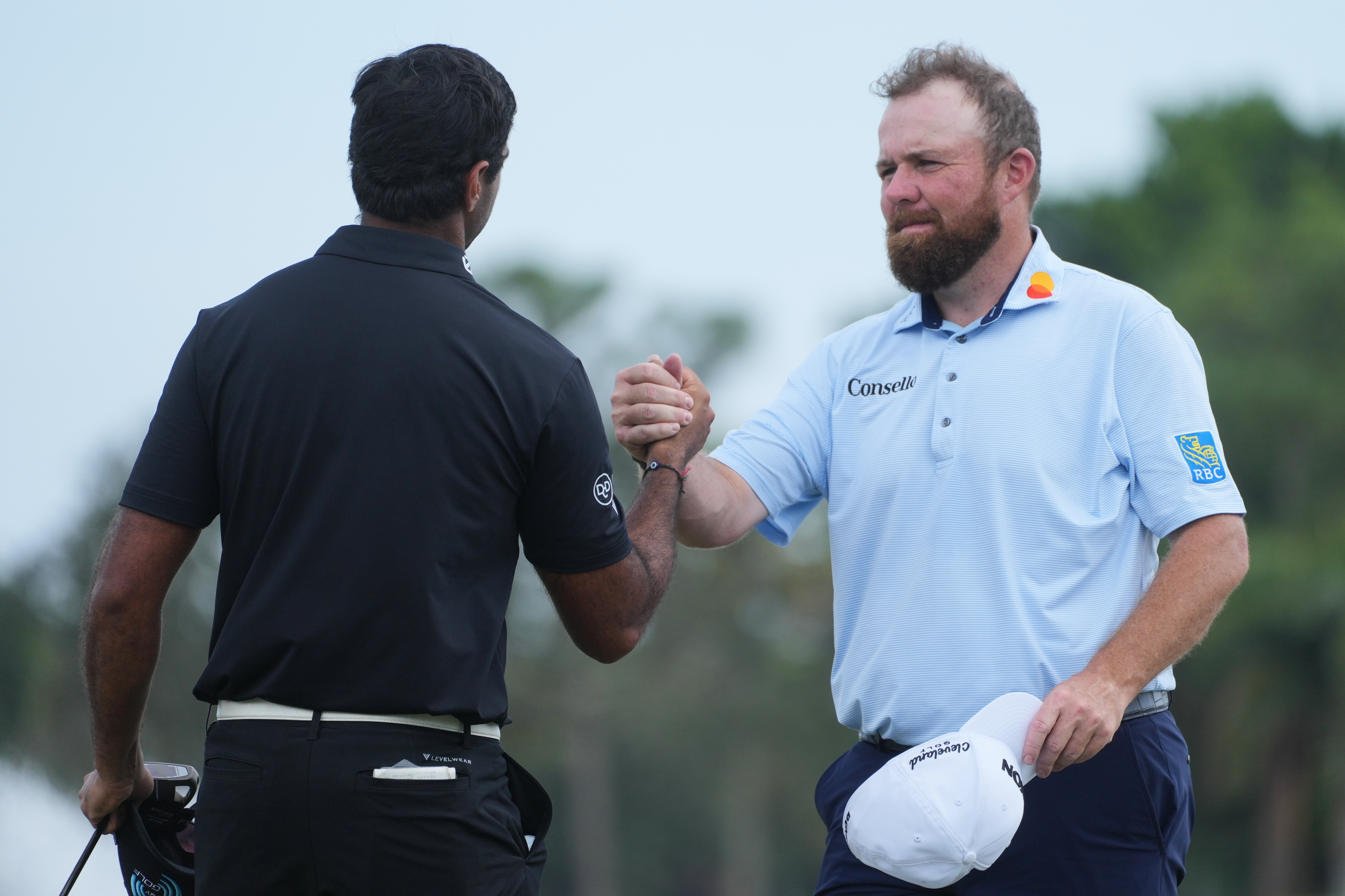 Shane Lowry of Ireland shakes hands with Aaron Rai of England, at the end of the third round of the Cognizant Classic golf tournament, Saturday, Feb. 28, 2026, in Palm Beach Gardens, Fla.