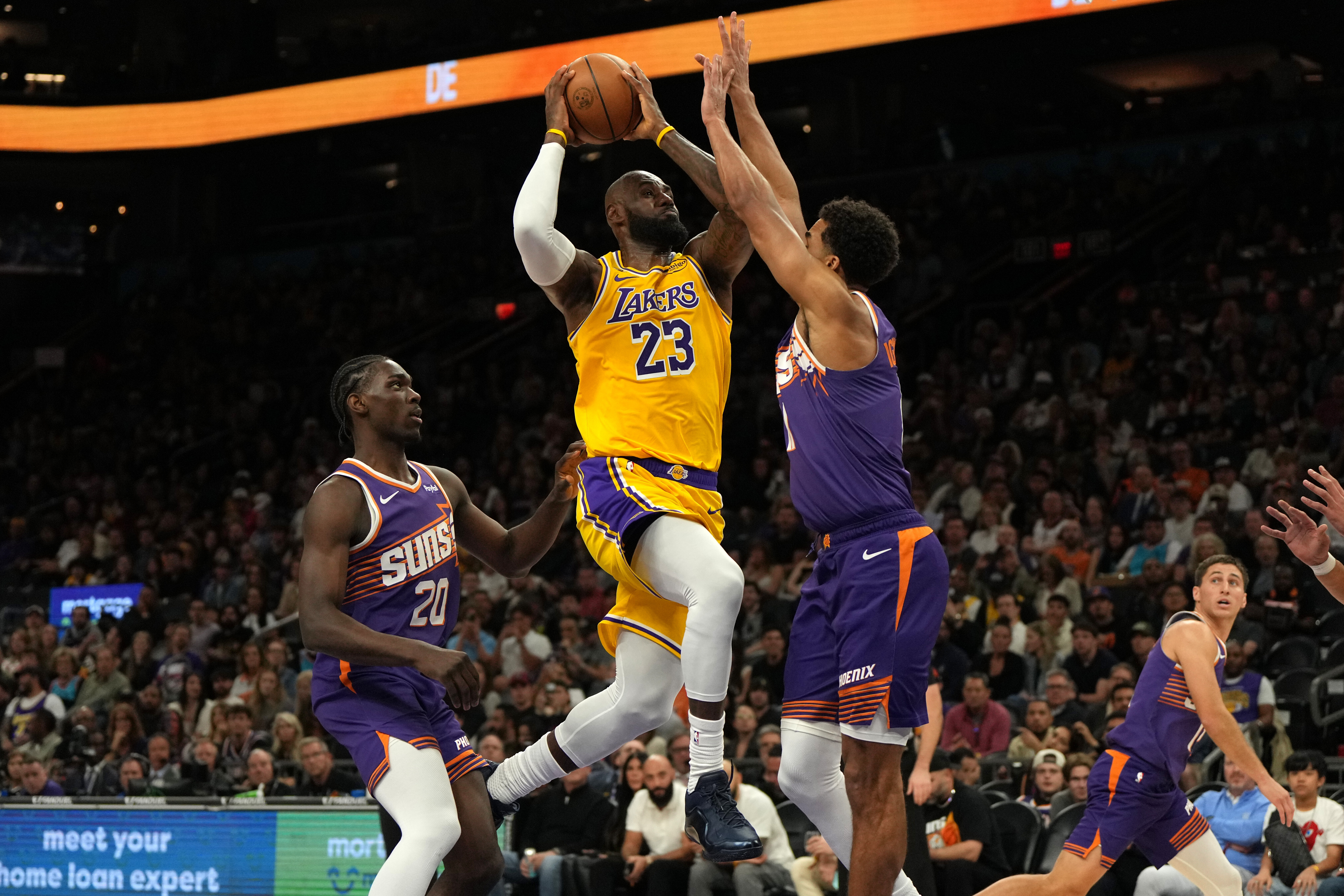 Los Angeles Lakers forward LeBron James drives between Phoenix Suns forward Rasheer Fleming (20) and forward Oso Ighodaro during the first half of an NBA basketball game, Thursday, Feb. 26, 2026, in Phoenix. 
