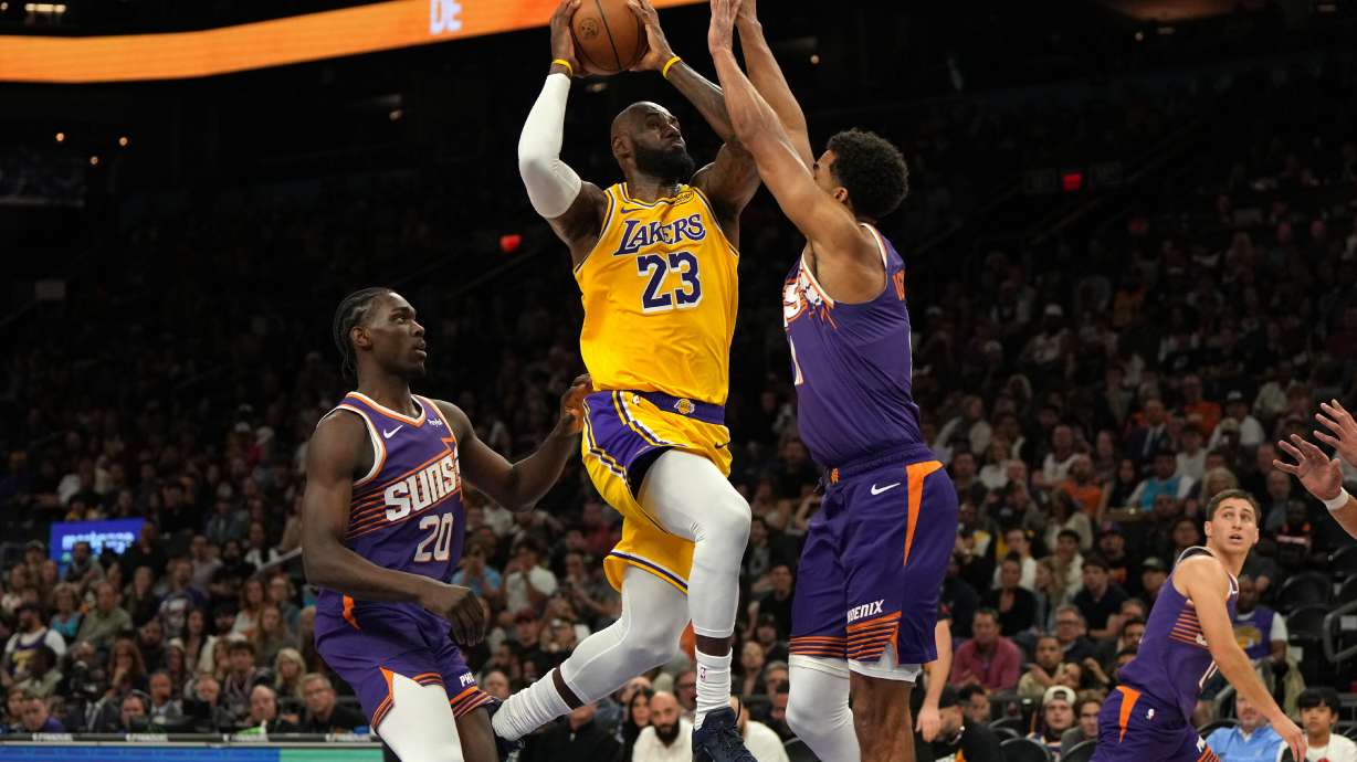 Los Angeles Lakers forward LeBron James drives between Phoenix Suns forward Rasheer Fleming (20) and forward Oso Ighodaro during the first half of an NBA basketball game, Thursday, Feb. 26, 2026, in Phoenix.