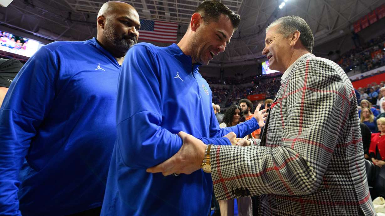 Florida head coach Todd Golden, center, shakes hands with Arkansas head coach John Calipari, right, before an NCAA college basketball game, Saturday, Feb. 28, 2026, in Gainesville, Fla.