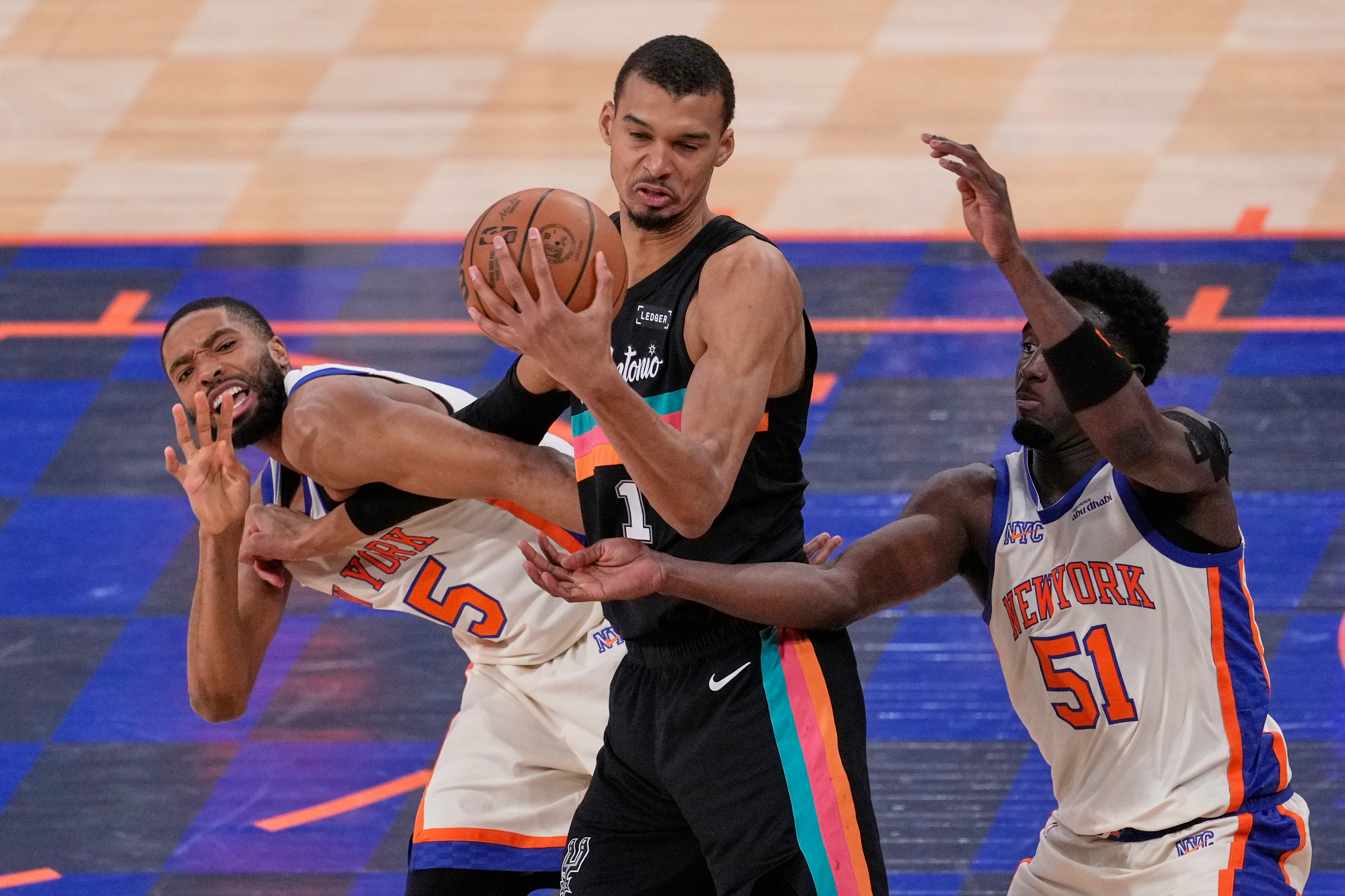 New York Knicks' Mikal Bridges, left, fouls San Antonio Spurs' Victor Wembanyama, center, while Bridges and Mohamed Diawara (51) try to get to the ball during the second half of an NBA basketball game Sunday, March 1, 2026, in New York.