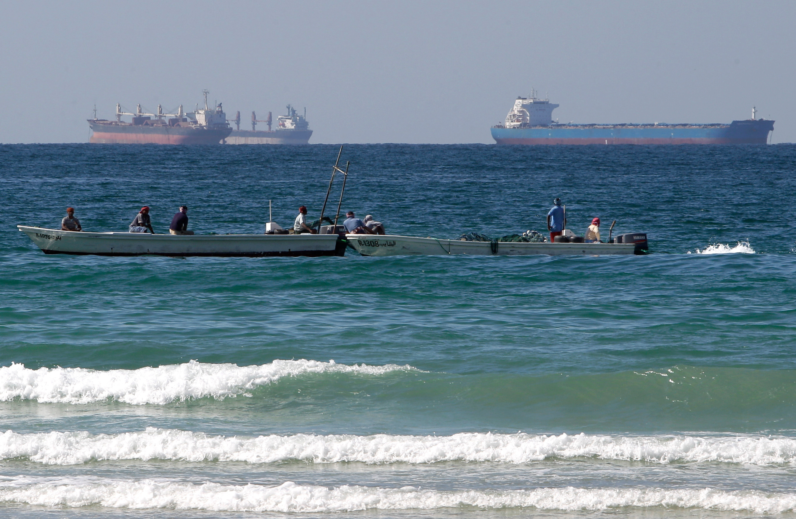 Fishermen work in front of oil tankers south of the Strait of Hormuz on Jan. 19, 2012, offshore the town of Ras Al Khaimah in the United Arab Emirates.
