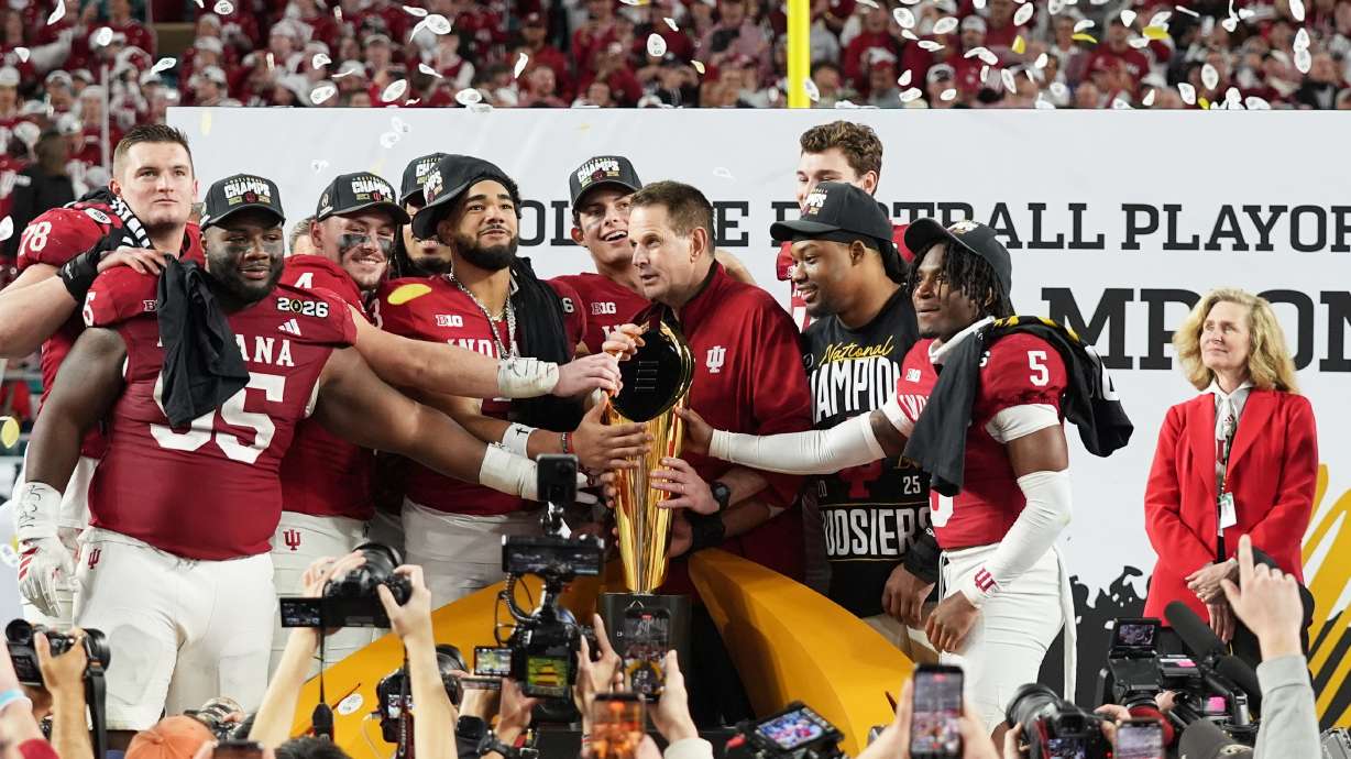 FILE - Indiana head coach Curt Cignetti, third from right, stands with players and the trophy after Indiana defeated Miami in a College Football Playoff national championship game, Jan. 19, 2026, in Miami Gardens, Fla.