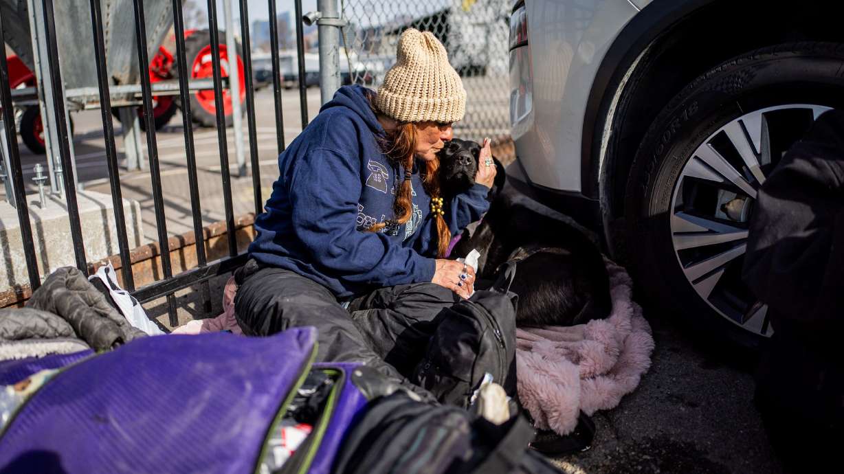 A person experiencing homelessness kisses her 1-year-old dog outside the Rescue Mission of Salt Lake shelter in Salt Lake City on Feb. 3. The city is considering a new camping ordinance that would expand prohibitions during overnight hours.