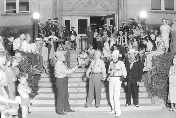 A photo of a group of people taken in front of the Bonneville County Courthouse. The man in the front center is believed to be Mayor/Governor Chase Clark of Idaho Falls, which would place this photo around 1937-1938.