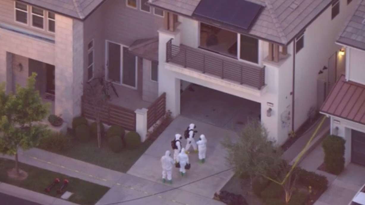 Several people wearing hazardous materials gear walking into a home in Irvine where FBI officials are investigating suspicious materials that were found at a home laboratory.