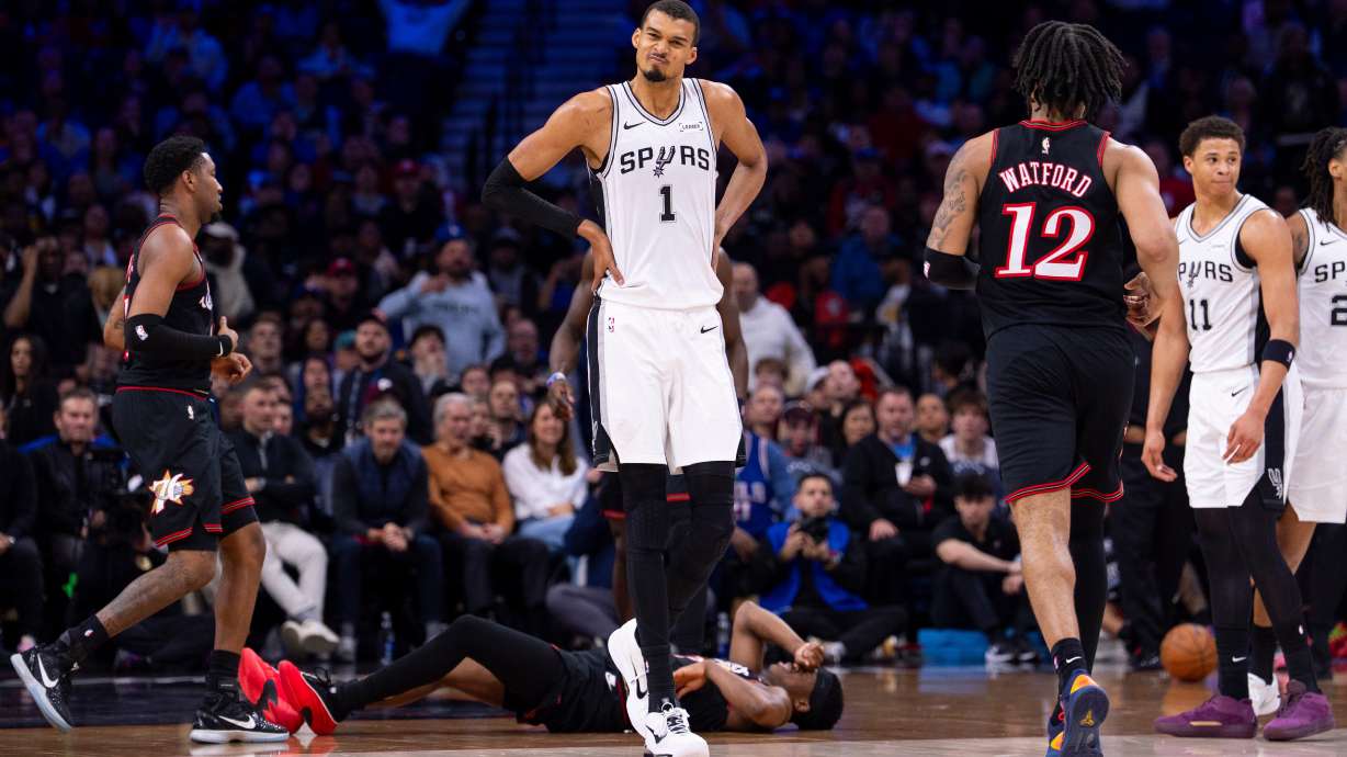 San Antonio Spurs' Victor Wembanyama, center, reacts to the foul by Carter Bryant, right, on Philadelphia 76ers' VJ Edgecombe, center floor, during the first half of an NBA basketball game, Tuesday, March 3, 2026, in Philadelphia.