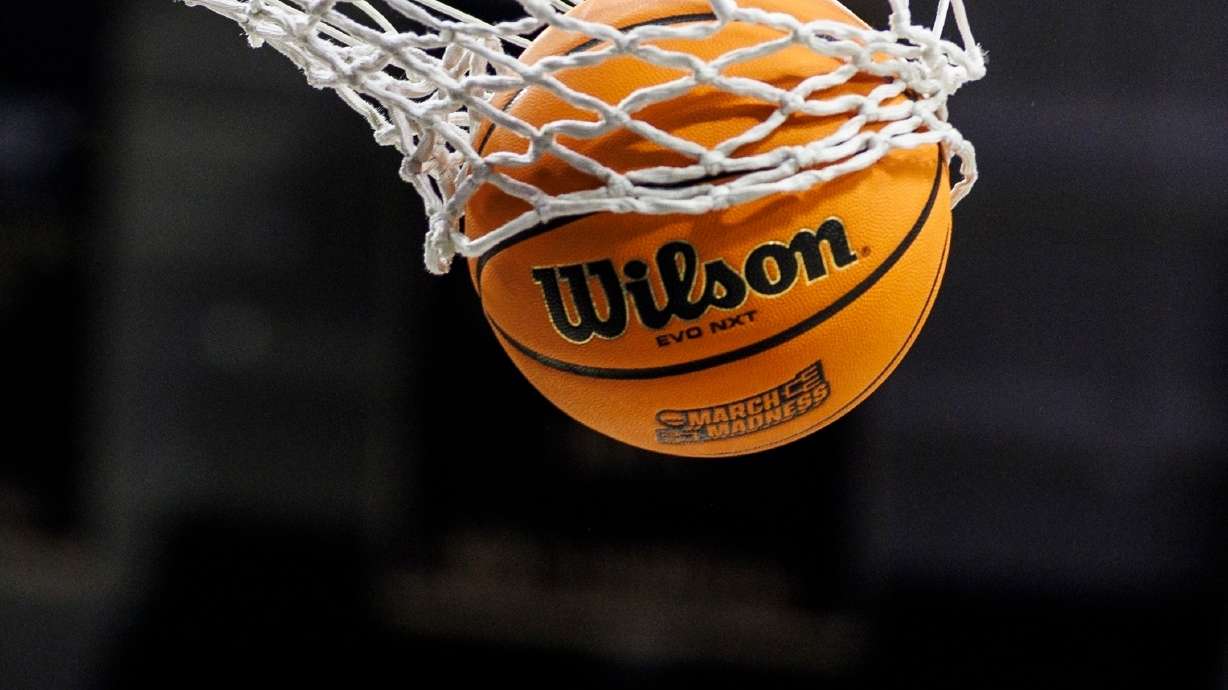 FILE - A basketball with a March Madness logo is seen going through a net prior to a second round of the NCAA college basketball tournament between Notre Dame and Michigan, March 23, 2025, in South Bend, Ind.