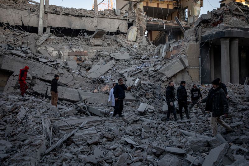 People stand in rubble at the site of an Israel and U.S. strike on a police station in Tehran, Iran, Tuesday. The war expanded significantly on Wednesday.