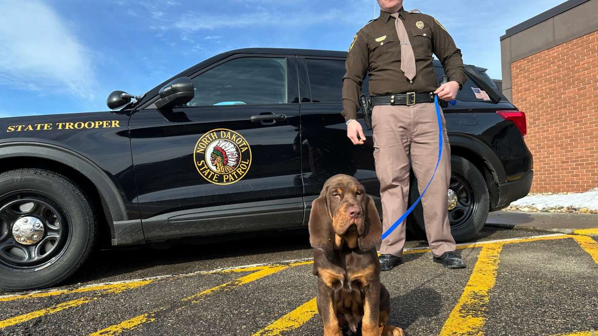 North Dakota Highway Patrol Trooper Dustin Pattengale and Beau, a bloodhound puppy, pose for a photo on Feb. 27, outside the Highway Patrol office in Fargo, N.D.