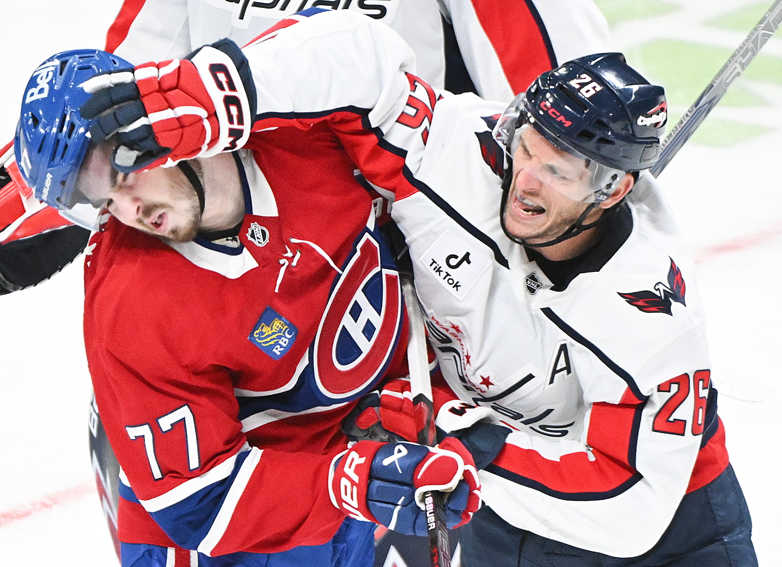 Washington Capitals' Nic Dowd (26) tries to face wash Montreal Canadiens' Kirby Dach (77) during the third period of an NHL hockey game in Montreal, Saturday, Feb. 28, 2026. 