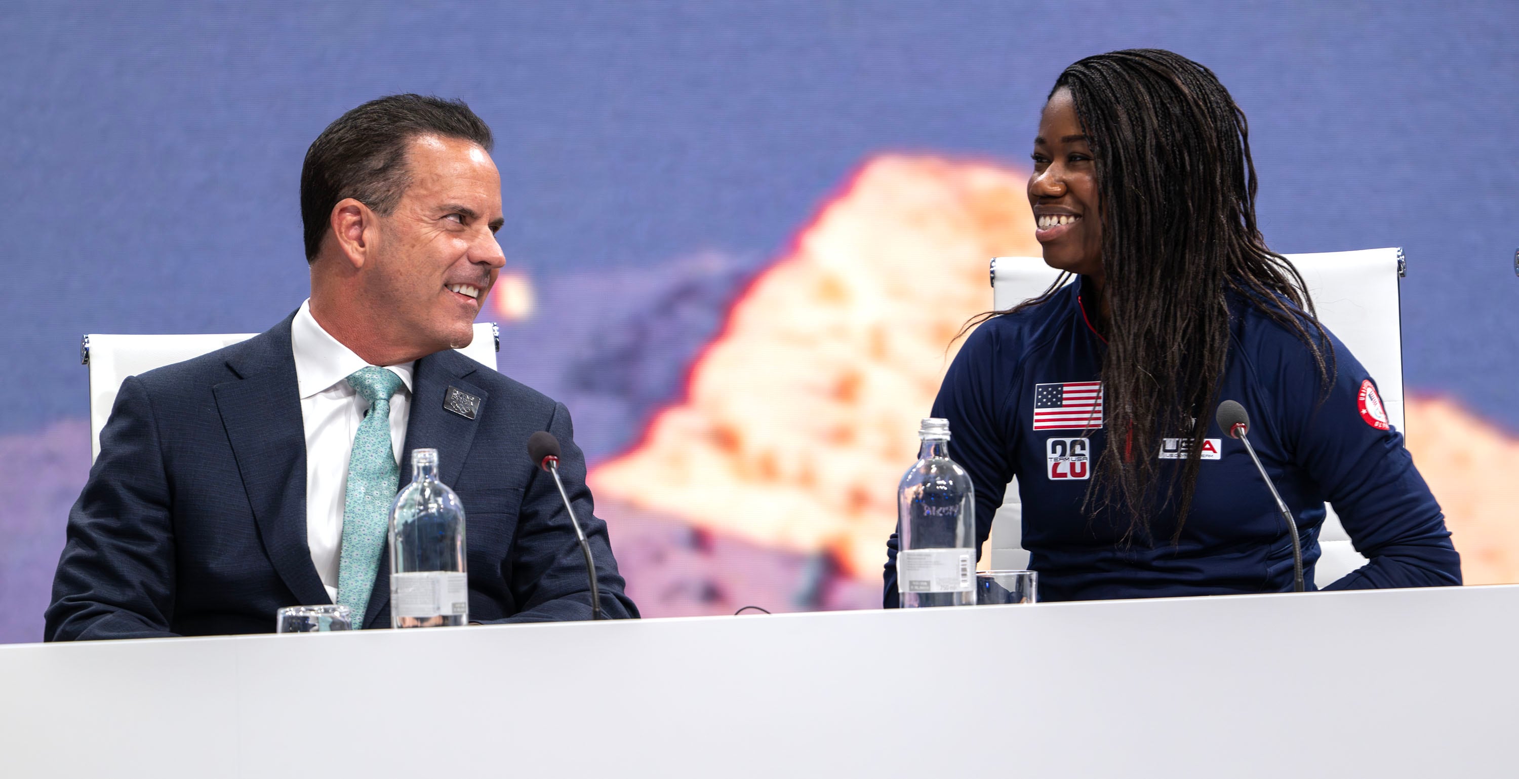 Brad Wilson, CEO of the Organizing Committee for the 2034 Olympic and Paralympic Winter Games, looks over at Olympic Speed Skater Erin Jackson, after she spoke to the IOC in Milan, Italy, on Tuesday, Feb. 3, 2026.