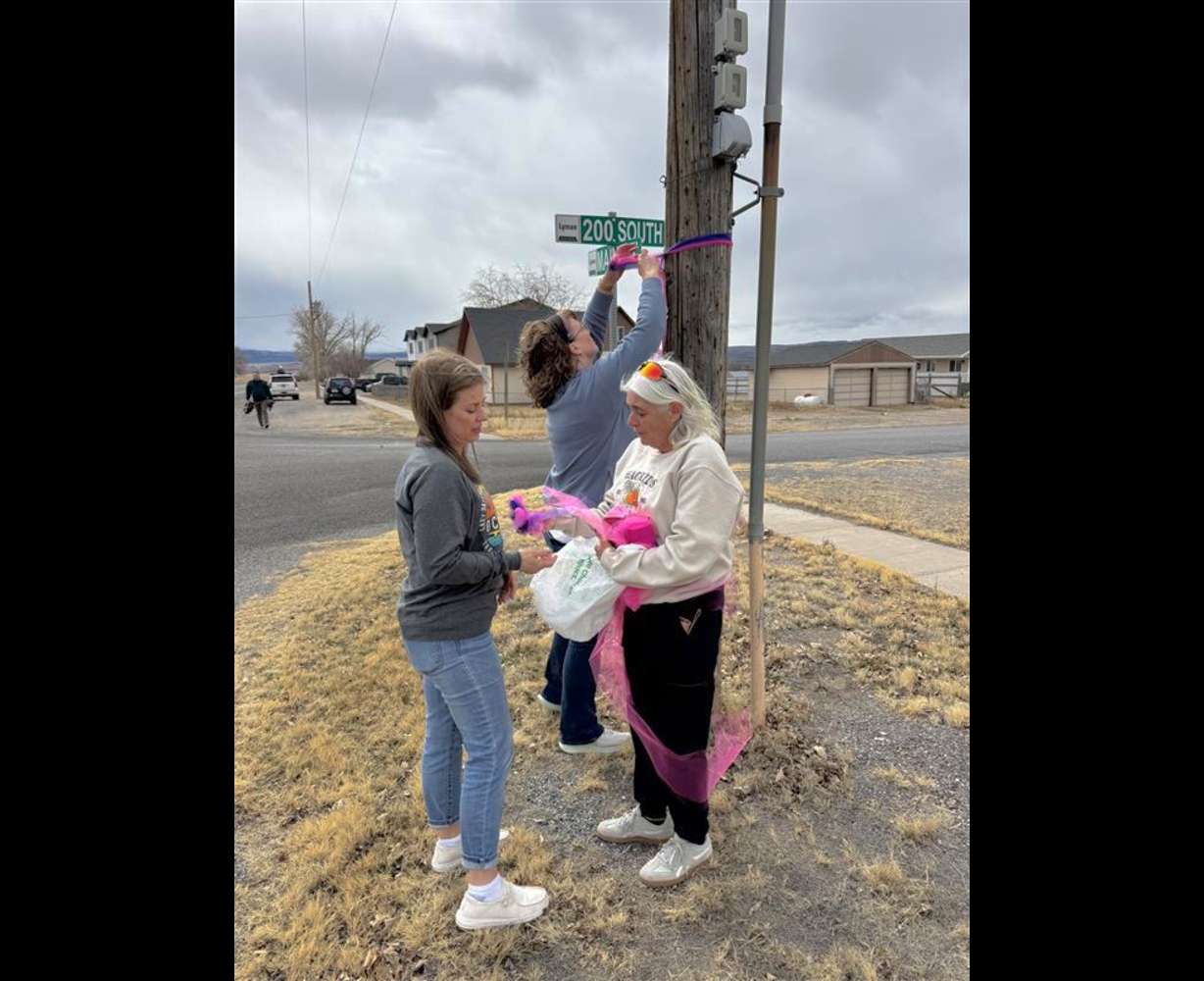 Mary Sorenson, Lori Chappell, and Melissa Robins tie pink ribbons in Lyman, Wayne County, Thursday. The ribbons are to remember three women police say were killed by a stranger.