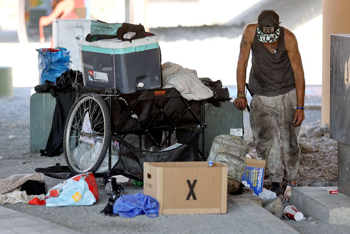 A man experiencing homelessness pauses while organizing his belongings under an overpass in Salt Lake City on July 25, 2025.