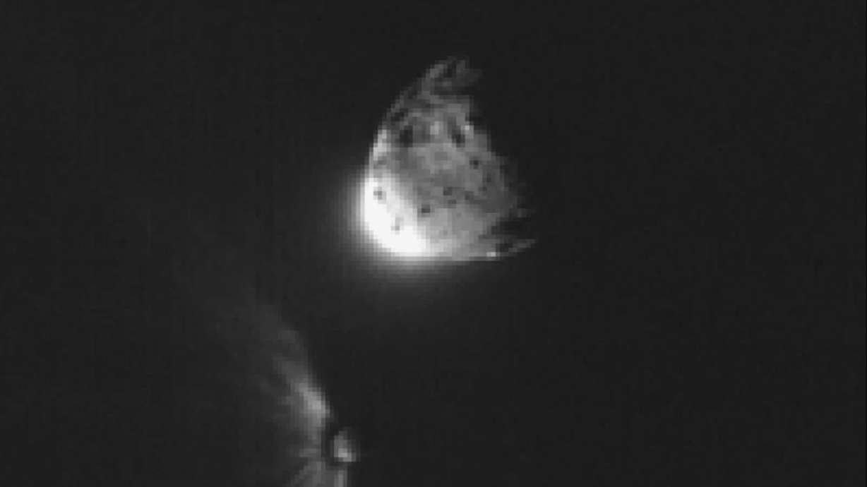 An impact plume emerges from the asteroid Dimorphos, left, after DART collides into it on Sept. 26, 2022, orbiting the larger asteroid Dimorphos. A new report on Friday showed the asteroid was nudged into a different orbit around the sun.