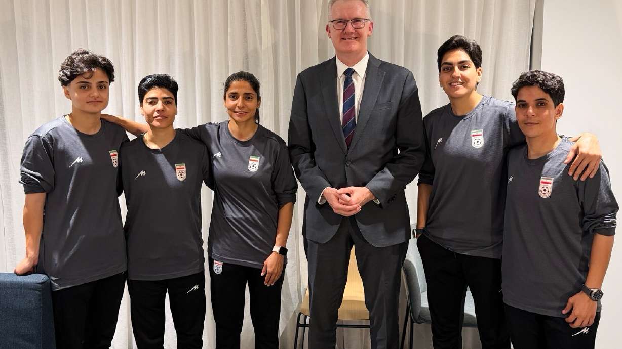 In this photo supplied by Australia's Minister for Home Affairs Tony Burke's office, the Minister Tony Burke, center, poses in an undisclosed location with five Iranian women soccer players who have been granted asylum in Australia, Tuesday, March 10, 2026.