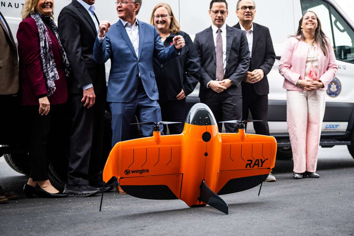 UDOT leadership and others gather for a photo behind a drone during a press conference to discuss UDOT’s selection to lead a federal pilot program testing advanced electric aircraft in Salt Lake City on Tuesday.