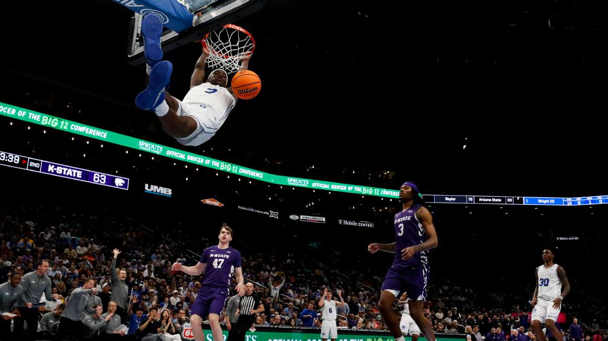 BYU forward AJ Dybantsa (3) hangs on the rim after a fast break dunk during the second half of the game against the Kansas State Wildcats during the 2026 Phillips 66 Big 12 Men's Basketball Tournament at the T-Mobile Center in Kansas City, Missouri, on Tuesday, March 10, 2026.