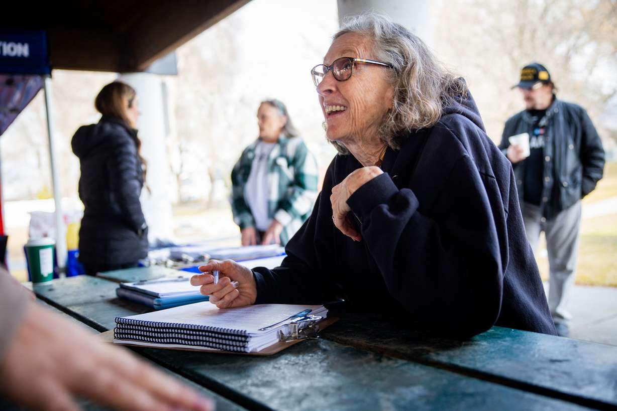 Vicki Anderson, from Cottonwood Heights, signs a petition to repeal Proposition 4 at a Turning Point Action signature gathering event at Union Park in Midvale on Feb. 12, 2026.