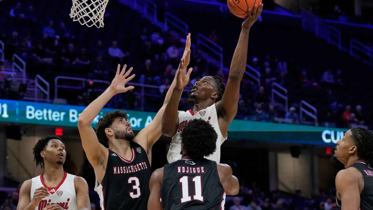 Miami forward Antwone Woolfolk shoots over Massachusetts' Leonardo Bettiol (3) and Jayden Ndjigue (11) in the first half of an NCAA college basketball game in the quarterfinals of the Mid-American Conference tournament, Thursday, March 12, 2026, in Cleveland.