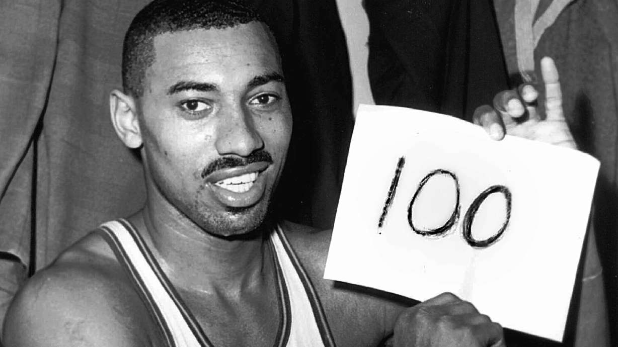 FILE - Philadelphia Warriors' Wilt Chamberlain holds a sign reading, "100," in the dressing room after he scored 100 points against the New York Knickerbockers, March 2, 1962, in Hershey, Pa.