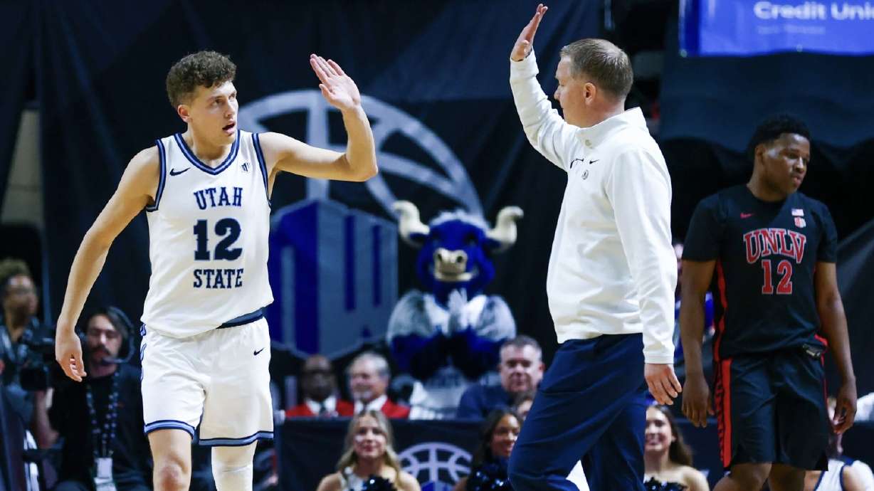 Utah State guard Mason Falslev (12) high-fives Utah State head coach Jerrod Calhoun as he subs out in the final minutes of the game in the second half of a Mountain West Tournament quarterfinal Thursday at the Thomas and Mack Center.