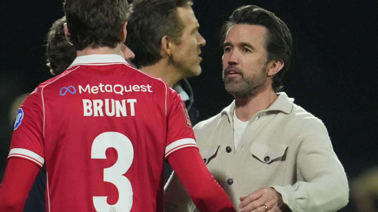 Actors and Wrexham owners Ryan Reynolds, center, and Rob McElhenney stand on the pitch after the fifth round FA Cup soccer match between Wrexham and Chelsea in Wrexham, Wales, Saturday, March 7, 2026.