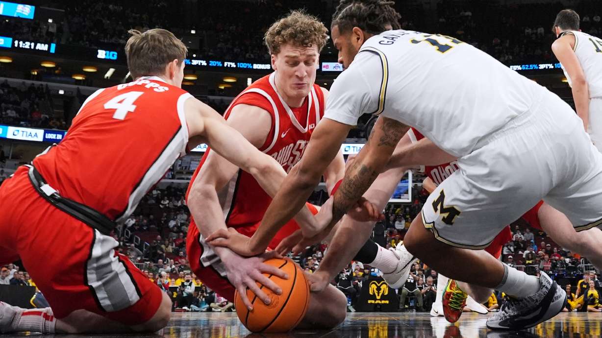 Ohio State center Christoph Tilly, center, battles for a loose ball against guard Gabe Cupps, left, and Michigan guard Roddy Gayle Jr. during the first half of an NCAA college basketball game in the quarterfinals of the Big 10 Conference tournament, Friday, March 13, 2026, in Chicago.