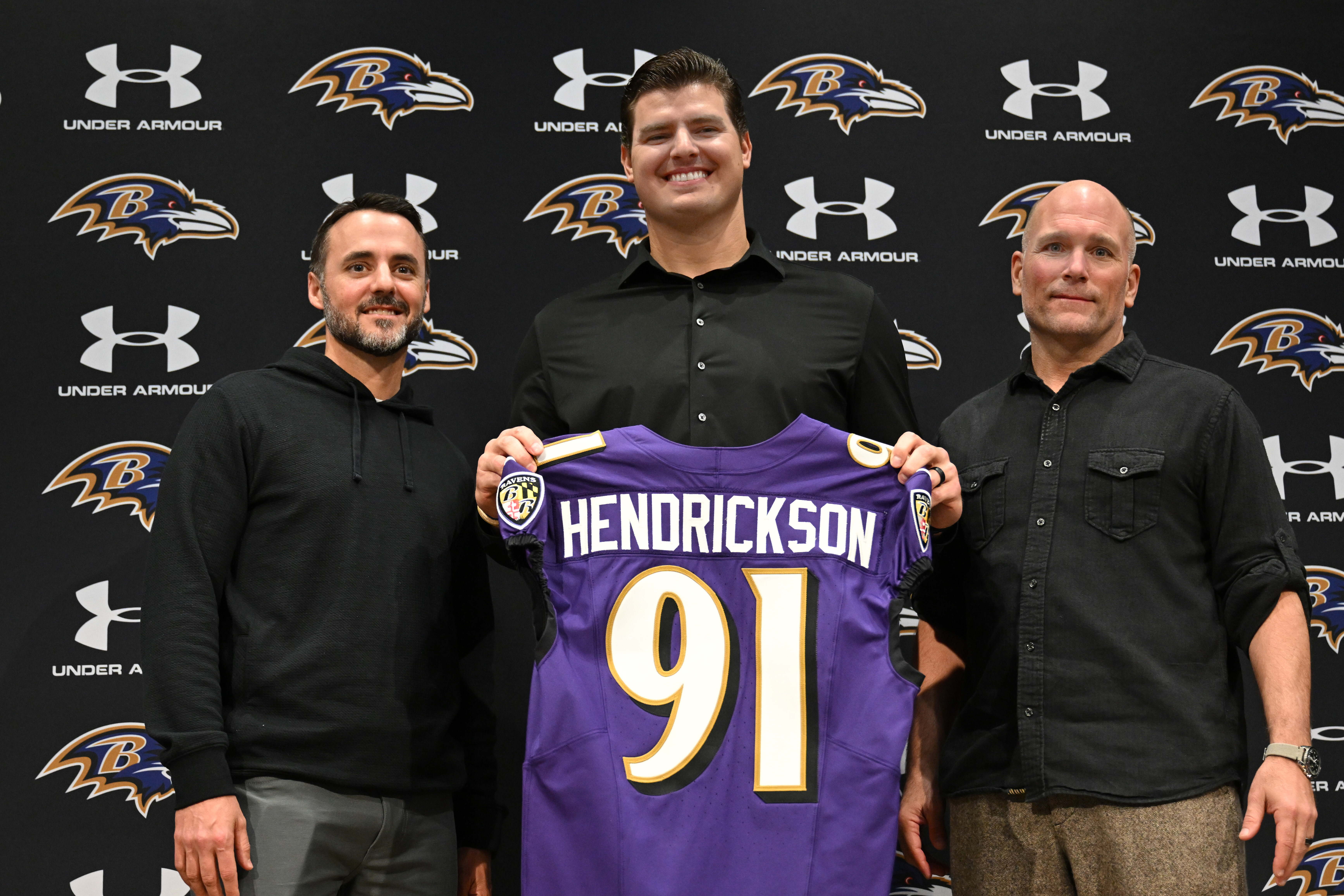 Baltimore Ravens, left to right, head coach Jesse Minter, defensive end Trey Hendrickson and general manager Eric DeCosta pose for a picture during an introductory NFL football press conference Friday, March 13, 2026, in Owings Mills, Md.