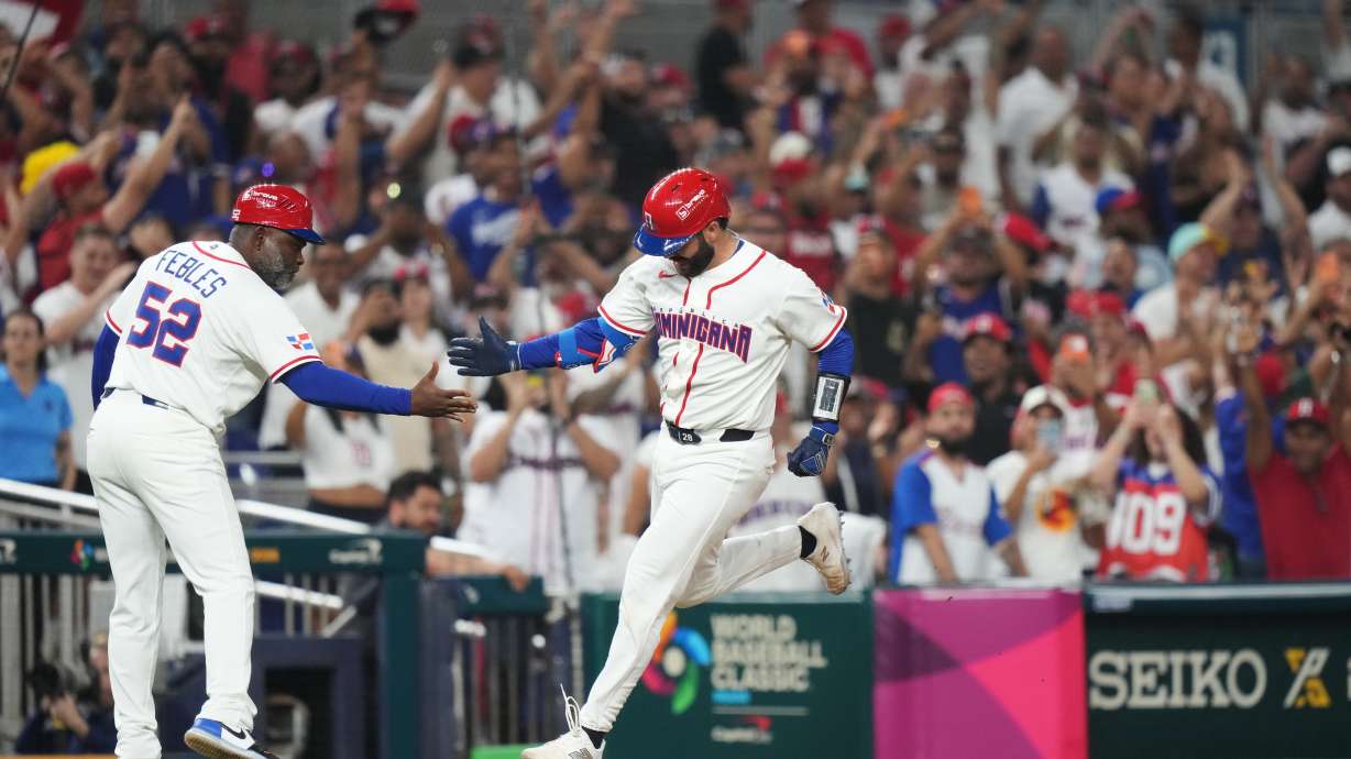 Dominican Republic's Austin Wells is congratulated by third base coach Carlos Febles as he heads for home after hitting a three-run home run to end the game early in the seventh inning of a World Baseball Classic quarterfinal game against South Korea, Friday, March 13, 2026, in Miami.