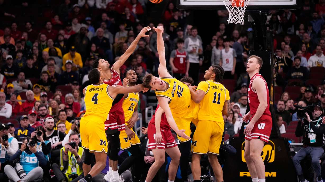 Wisconsin guard Nick Boyd, second from left, and Michigan forward Will Tschetter (42) battle for a rebound during the first half of an NCAA college basketball game in the semifinals of the Big 10 Conference tournament, Saturday, March 14, 2026, in Chicago.