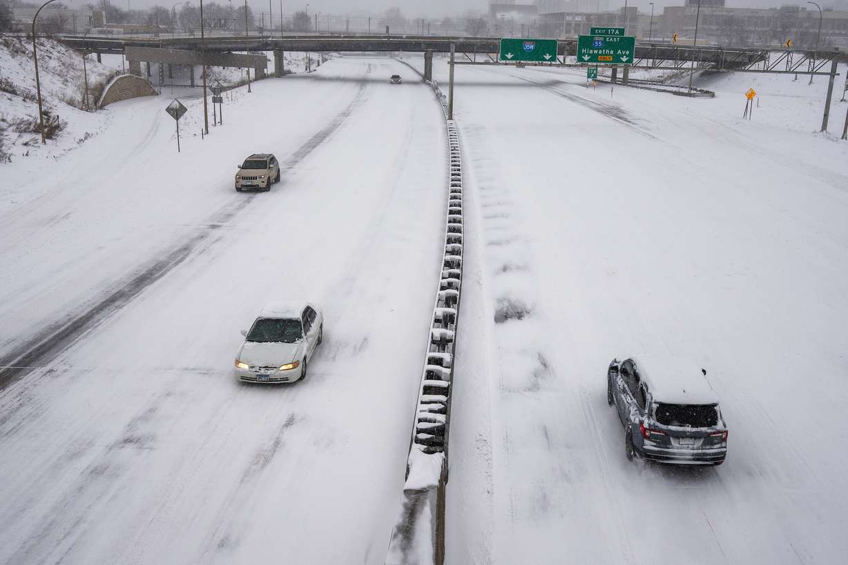 People drive on a snow-covered freeway during a snowstorm, Sunday, in Minneapolis.