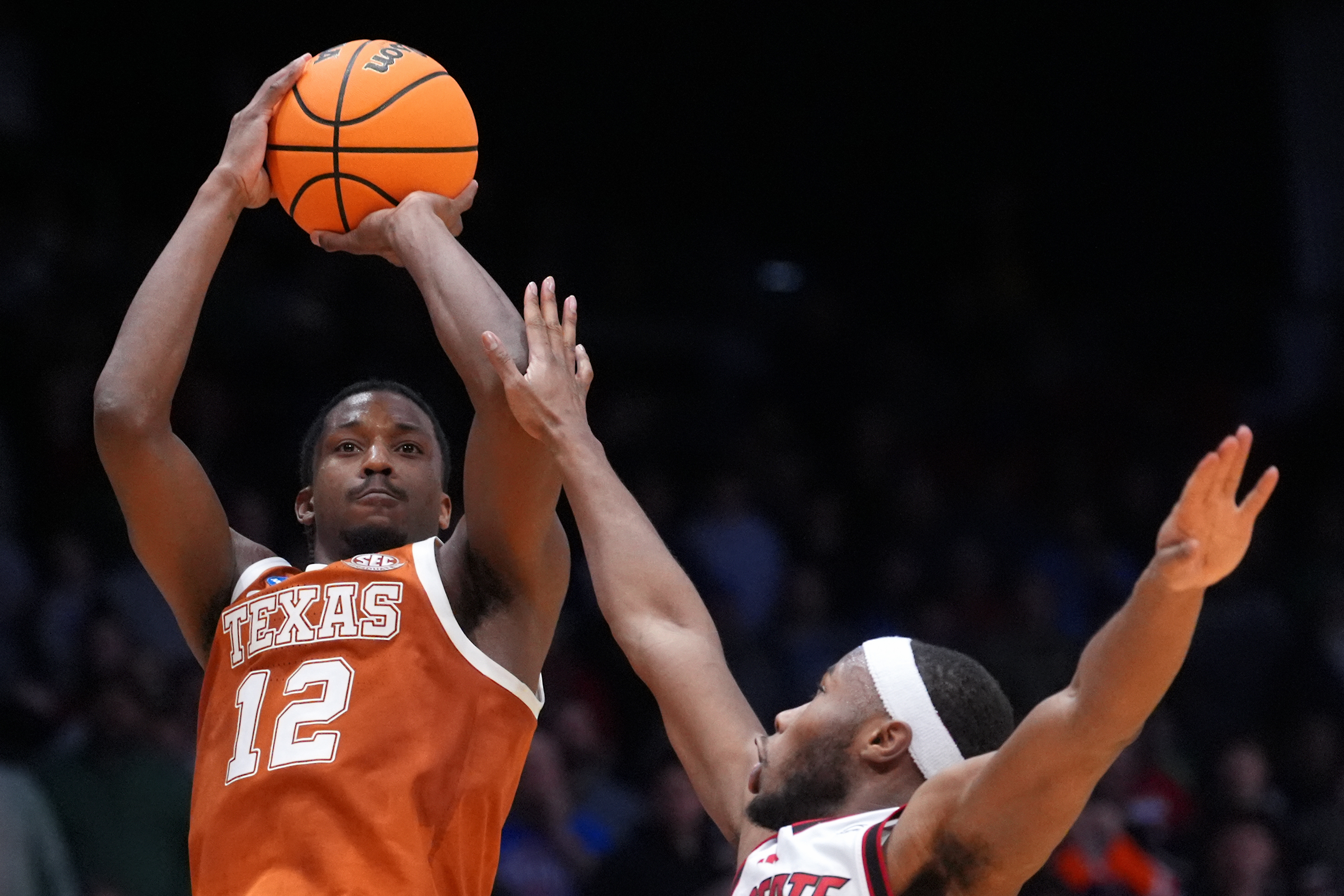 Texas guard Tramon Mark (12), left, scores a go-ahead basket with 1 second remaining during the second half in a First Four college basketball game in the NCAA Tournament against North Carolina State, Tuesday, March 17, 2026, in Dayton, Ohio.