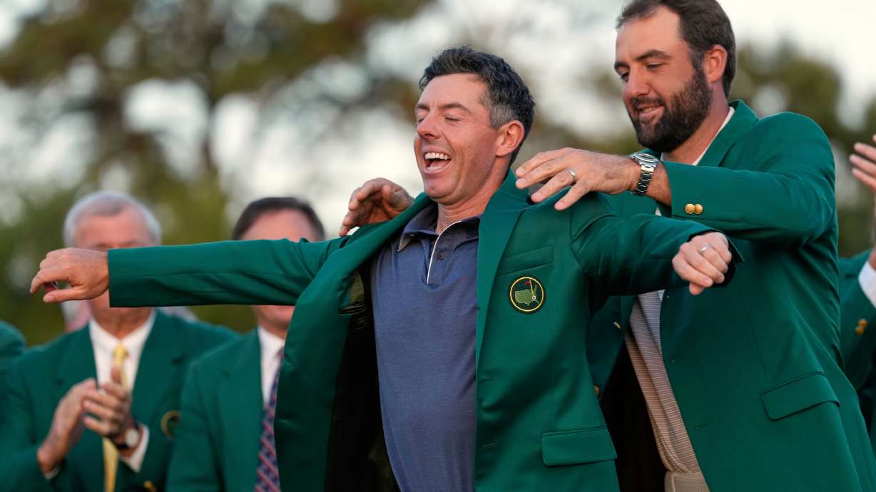 FILE - Scottie Scheffler puts the green Jacket on winner, Rory McIlroy, of Northern Ireland, at the Masters golf tournament, April 13, 2025, in Augusta, Ga.
