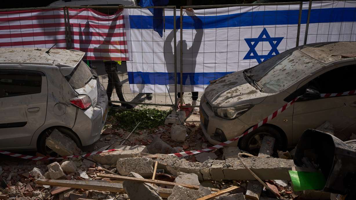 Israeli authorities hang Israeli and U.S. flags at the site struck by an Iranian missile that killed two people, in Ramat Gan, Israel, Wednesday.