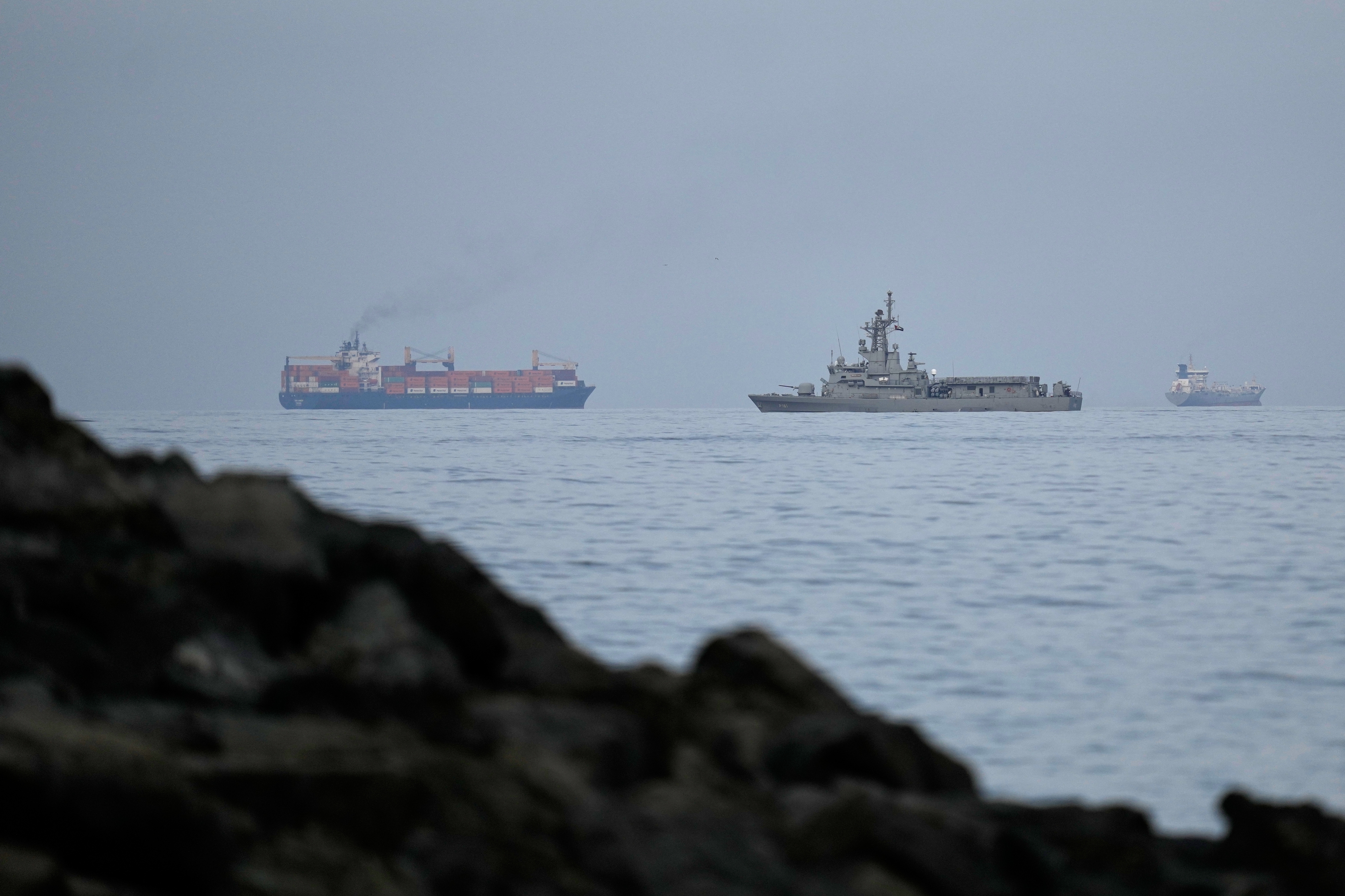 A UAE navy ship sails next to a cargo ship in the Strait of Hormuz as seen from Khor Fakkan, United Arab Emirates, March 11. The UAE suspended trade with Iran on Wednesday as the UAE claimed it came under renewed Iranian missile fire.