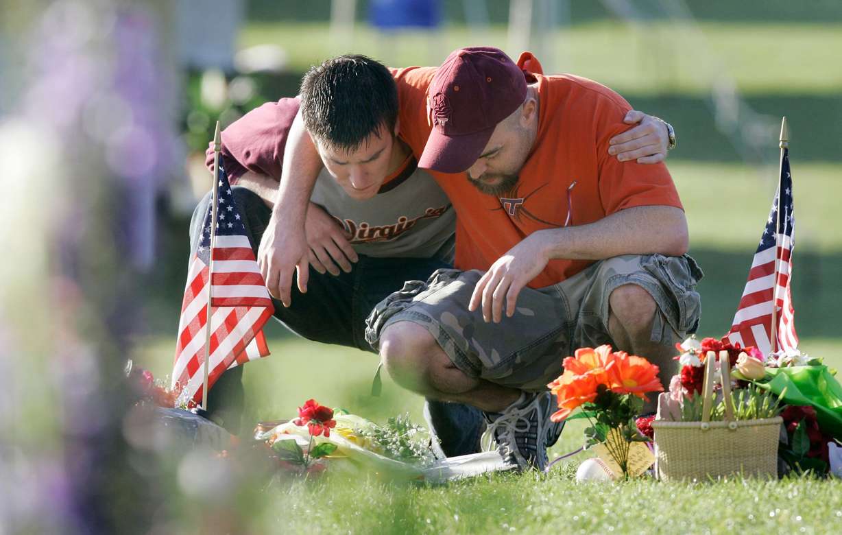 Joshua Stevens, of Blacksburg, Va., embraces former Virginia Tech student Russell Miller of Richmond, Va., as they visit the makeshift memorial on the campus of the university in Blacksburg, Va., April 21, 2007. A survivor of the shooting spoke at the University of Utah's annual campus safety summit on Thursday.